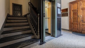 A staircase leading to an elevator, a wooden door, and a glass door with a sign. - Appartamento Re Umberto by Wonderful Italy (Turin)