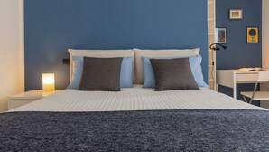 A bedroom with a bed, bedside tables, a desk, and a chair. - Appartamento Re Umberto by Wonderful Italy (Turin)