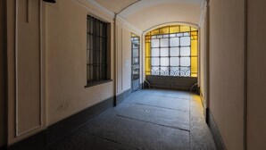 A hallway with a curved ceiling, a window with decorative bars, and a door with a sign. - Appartamento Re Umberto by Wonderful Italy (Turin)
