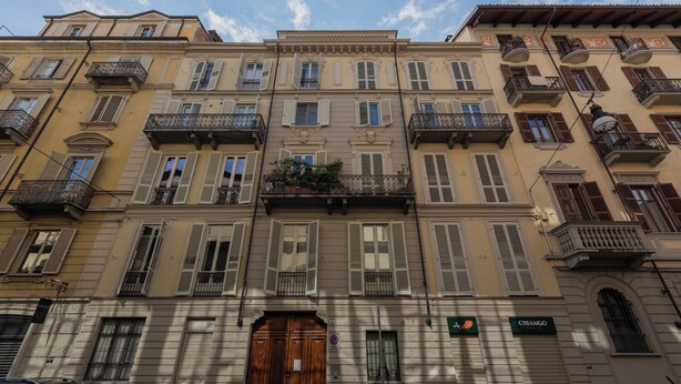 A multi-story building with a central entrance, balconies, and a sign indicating a business establishment. - Appartamento Re Umberto by Wonderful Italy (Turin)