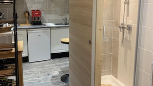 A modern bathroom with a glass-enclosed shower, a wooden door, and a tiled floor.