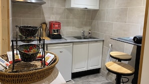 A compact kitchen with a built-in espresso machine, a sink, and a small dining area with stools.