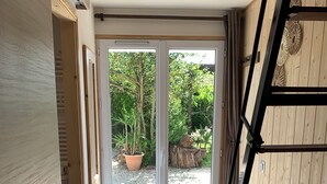 A room with a sliding glass door leading to an outdoor area with a wooden deck and potted plants.