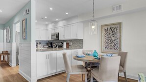 Une cuisine moderne avec des meubles blancs, un îlot central et un coin repas comprenant des chaises et une table.