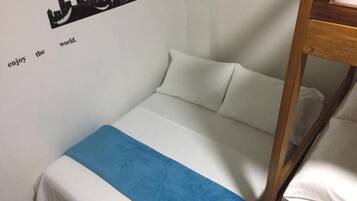 Een enkel bed met een wit- en blauwe spreideken, een houten hoofdbord, en een muur met een stadsgezicht-stickers en de tekst