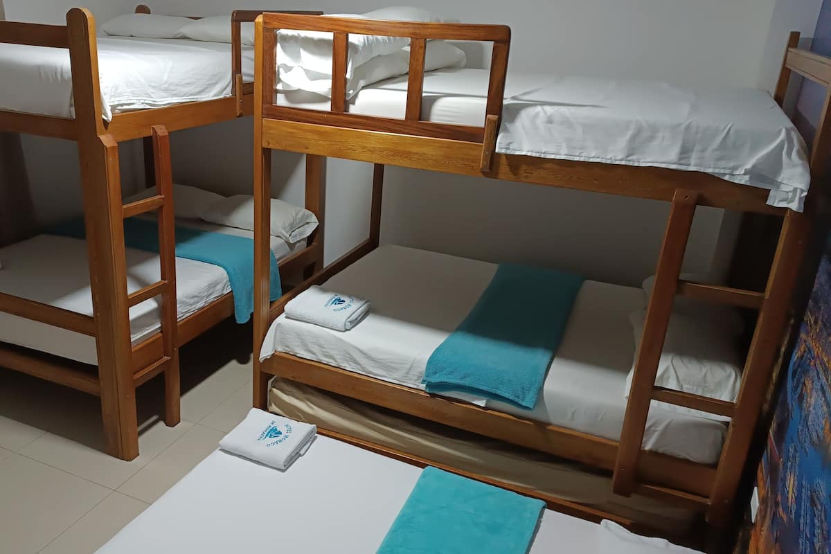 Una habitación con tres literas de madera, cada una con ropa de cama blanca y una toalla azul.