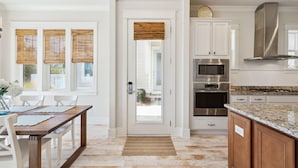 A modern kitchen with white cabinetry, stainless steel appliances, and a granite countertop. - Heated Pool - Golf Cart+Bikes - Close to Beach! (Inlet Beach)
