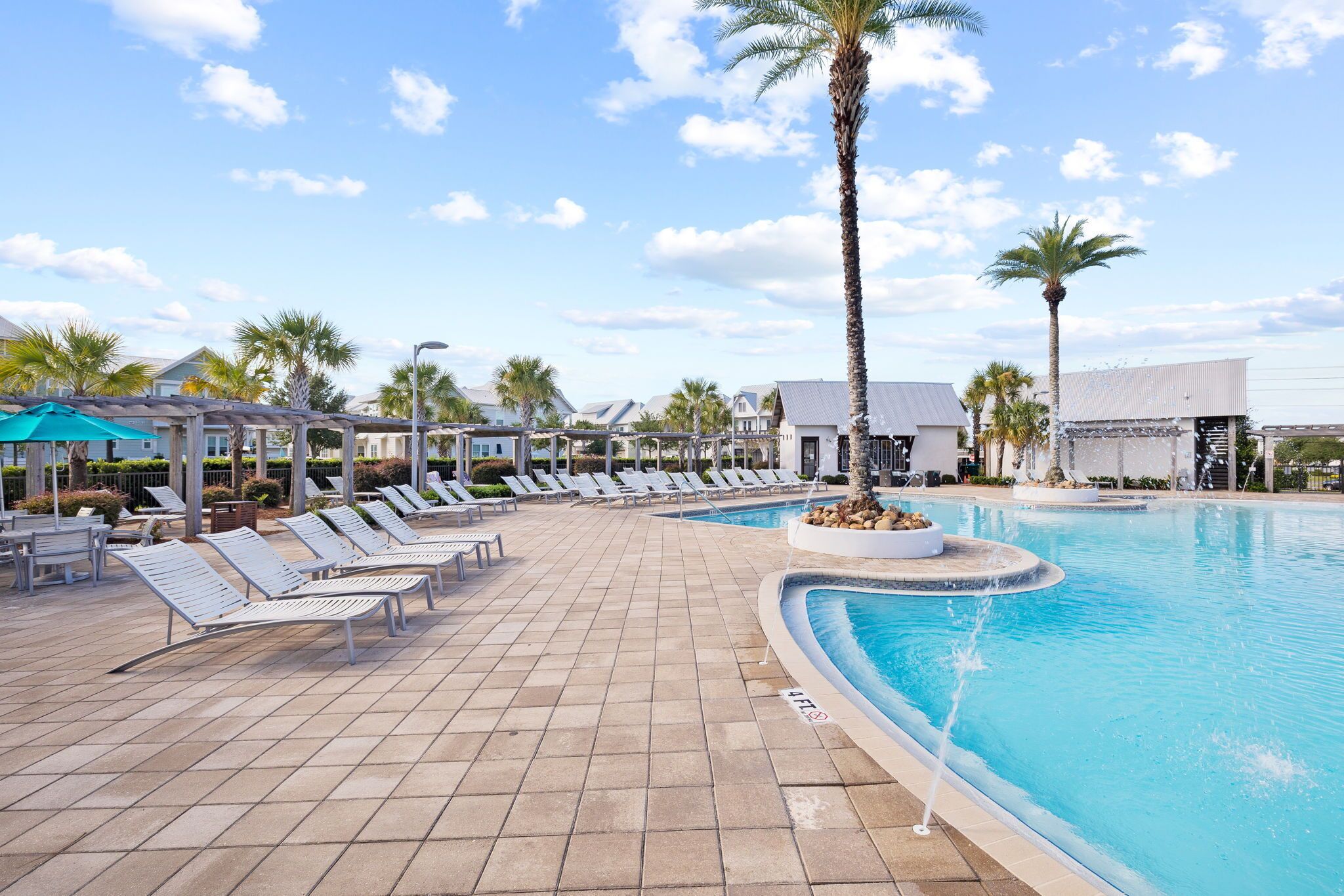 A pool area with lounge chairs and palm trees.
