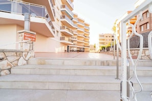 Un edificio residencial de varios pisos con balcones, un letrero de propiedad privada y una escalera de piedra que conduce a la entrada.