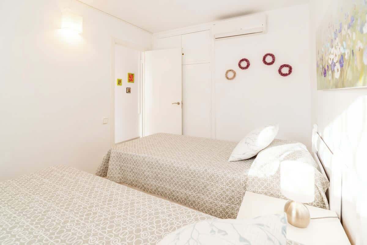 A hotel room with two beds, a door, an air conditioning unit, and a wall with three circular decorations.
