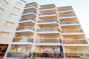 A multi-story residential building with balconies, air conditioning units, and a gated entrance.