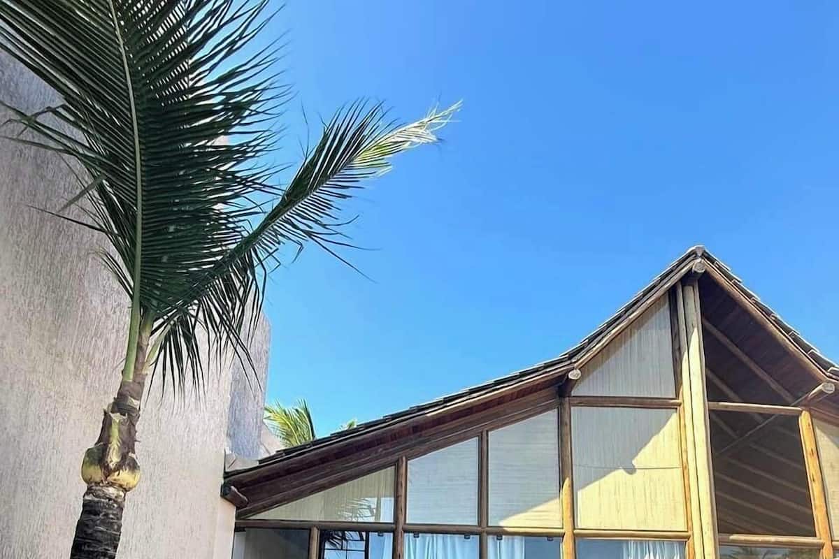 A house with a wooden deck, a swimming pool, and large windows.
