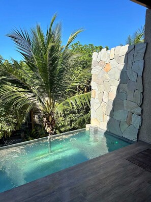 A clear blue sky, a stone wall, and a pool with clear water.