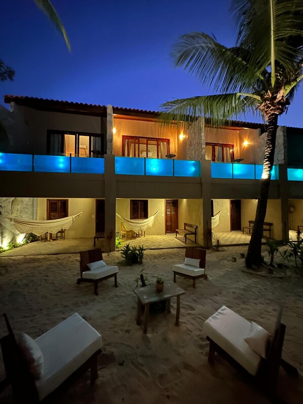 A two-story building with a balcony, hammocks, and outdoor seating.