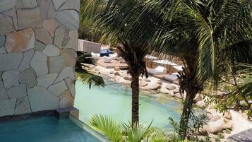 Una piscina con agua cristalina, rodeada por un muro de piedra y palmeras.