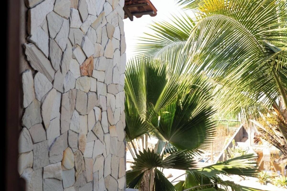 A stone wall with a tiled roof, a pool, and palm trees.