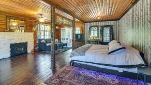 L’intérieur d’une cabane en rondins, avec un grand lit, une cheminée et un plafond en bois.