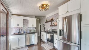 Une cuisine moderne avec des meubles blancs, des appareils en acier inoxydable et un tapis à motifs.