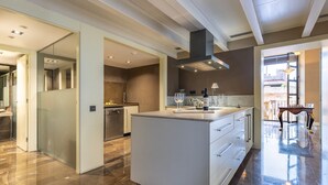 Cozinha moderna com ilha central, área de jantar com mesa de madeira e vista para o exterior.