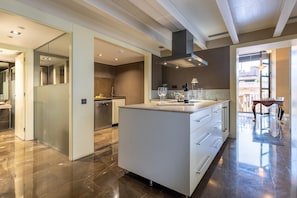 Une cuisine moderne dotée d’un îlot central, d’un coin repas avec une table en bois et offrant une vue sur l’extérieur.