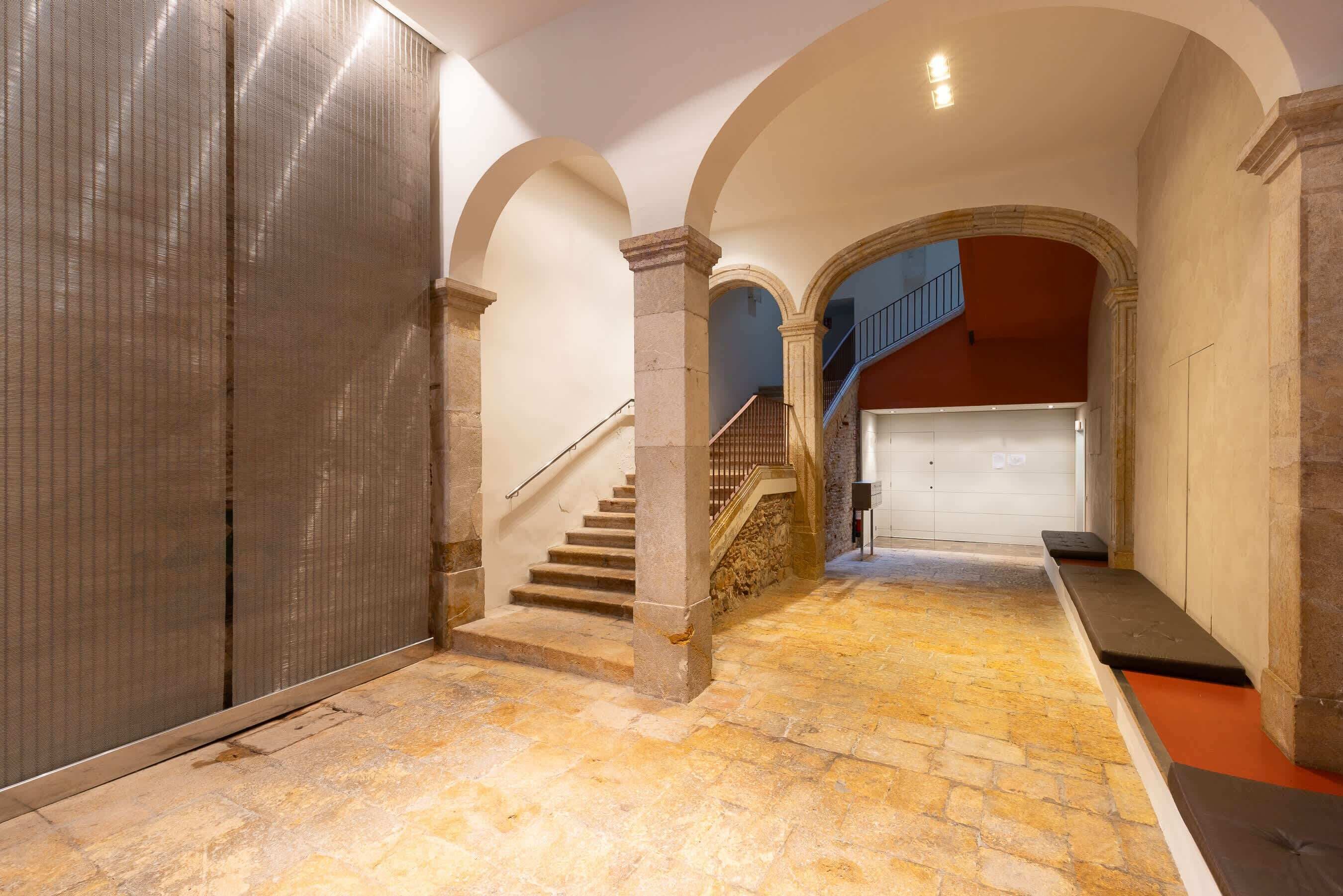 A hallway with stone flooring, a staircase, and a garage door.
