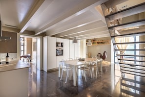 Een moderne keuken met een eetgedeelte, een trap en uitzicht naar buiten.
