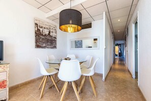 Un espace repas avec une table ronde, des chaises blanches et un luminaire suspendu.