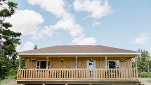 Eine Holzhütte mit Veranda, Fenstern und einer Tür.