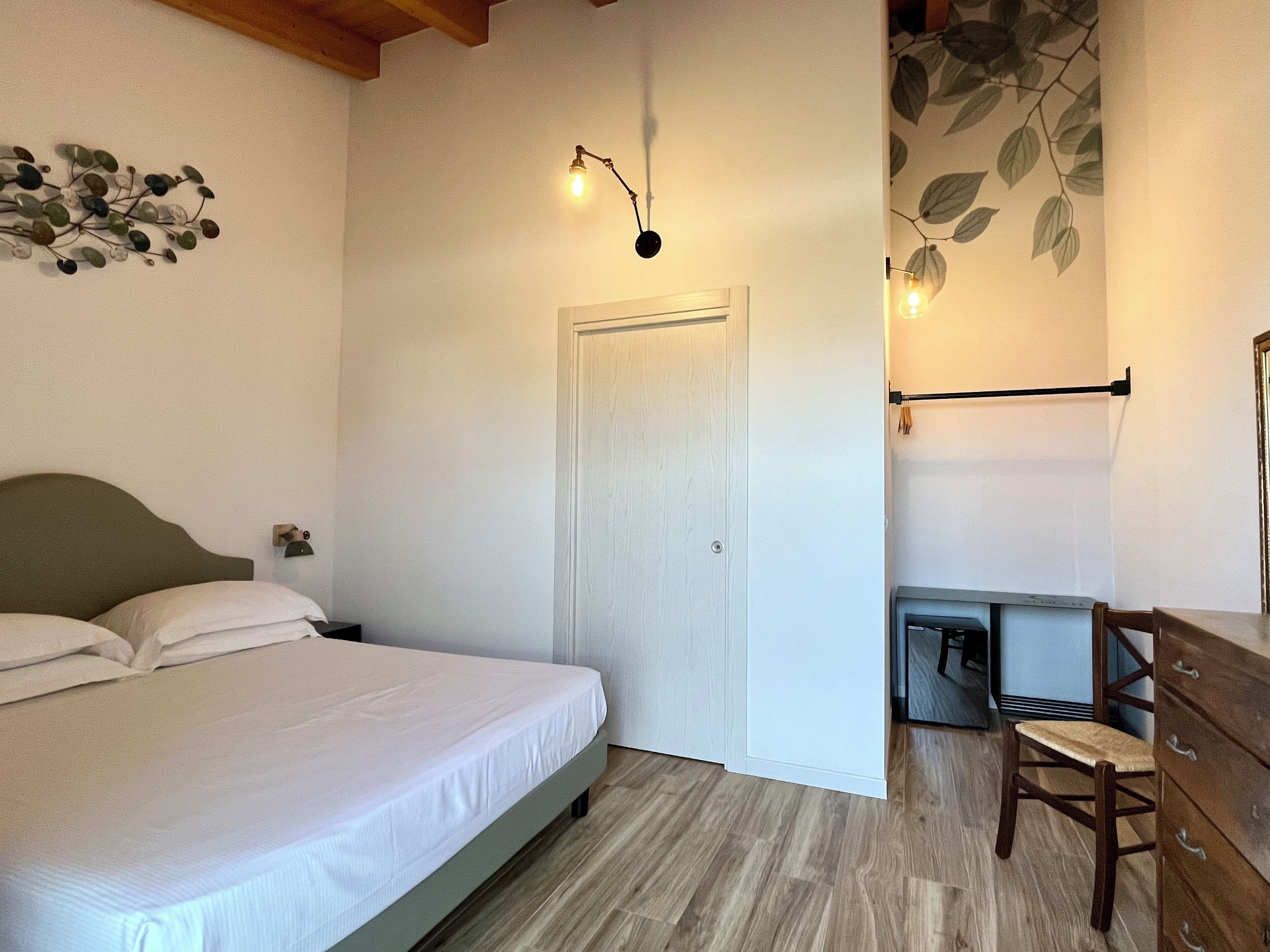 A bedroom with a bed, a desk, a chair, a wardrobe, and a door.