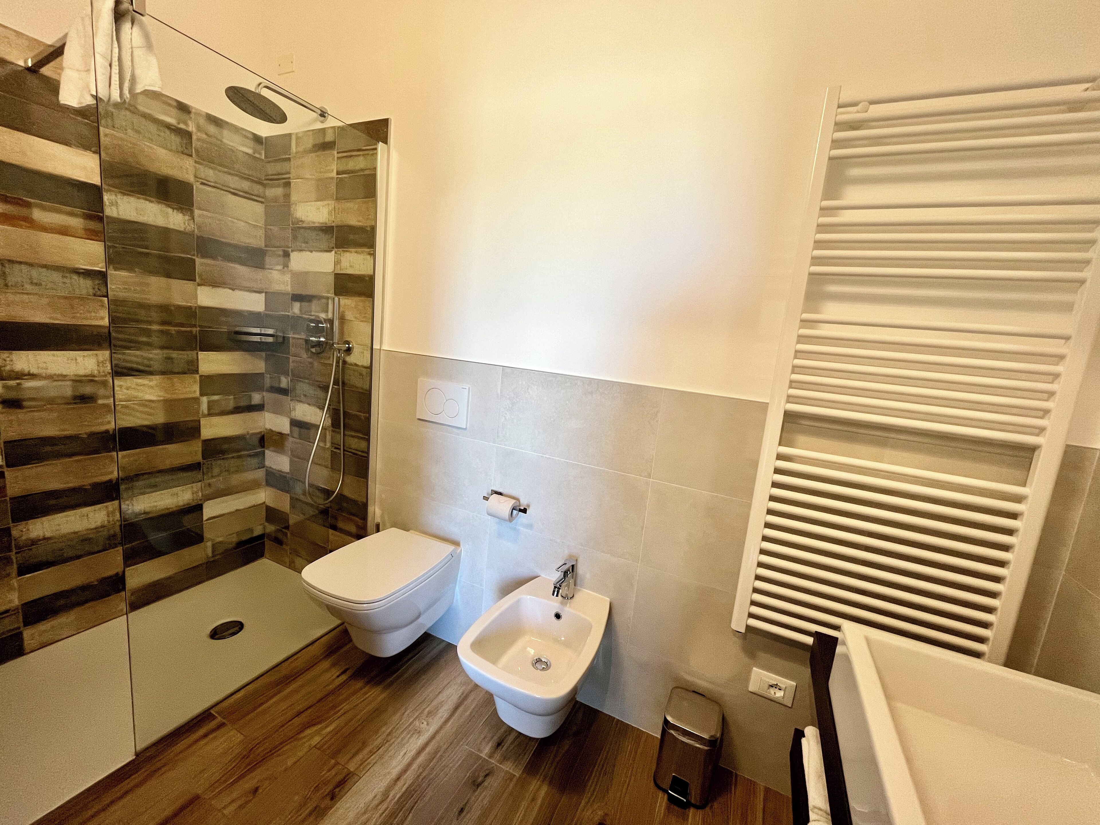 A modern bathroom with a glass shower enclosure, a toilet, a bidet, and a sink.