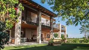 A two-story house with a balcony, outdoor seating, and a well-maintained lawn. - Agriturismo Casale ai Prati (Latisana)