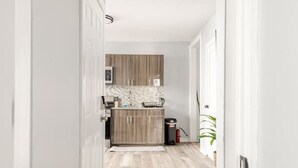 A narrow hallway leading to a kitchen with wooden cabinets and a tiled backsplash. - Modern 2 Bed in BlackRock (Bridgeport)