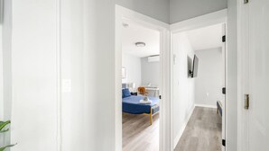 A hallway leading to a bedroom with a bed, bedside table, and a TV mounted on the wall. - Modern 2 Bed in BlackRock (Bridgeport)