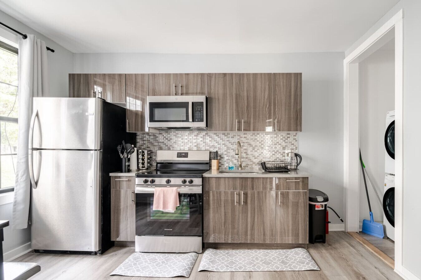 Una cocina moderna con un refrigerador de acero inoxidable, un microondas, una estufa y armarios de madera.