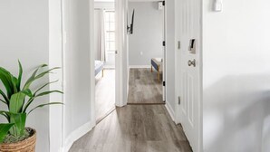 A hallway with a wooden floor, white walls, and a potted plant. - Modern 2 Bed in BlackRock (Bridgeport)