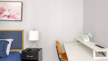 Une chambre à coucher comprenant un lit, un bureau, une chaise, une lampe et un climatiseur fixé au mur.
