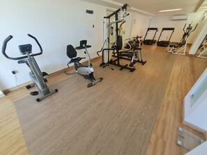 Un gimnasio con máquinas de cardio, equipo de levantamiento de pesas y una cinta de correr.