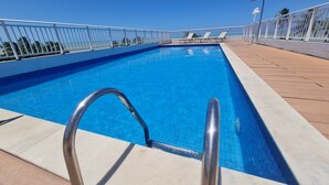 A swimming pool with a clear blue water, surrounded by a white metal railing and a wooden deck. - JARDINS DO ATLANTICO by Penareia.tur.br (João Pessoa)