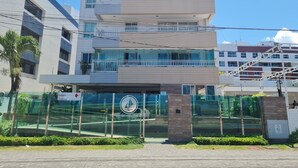 A multi-story building with a glass facade, balconies, and a sign indicating a security company. - JARDINS DO ATLANTICO by Penareia.tur.br (João Pessoa)