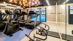 Un gimnasio con cintas de correr, elípticas y una máquina de remo.