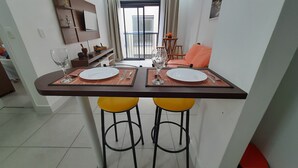 Un comedor con dos platos blancos, una copa y una pequeña mesa.