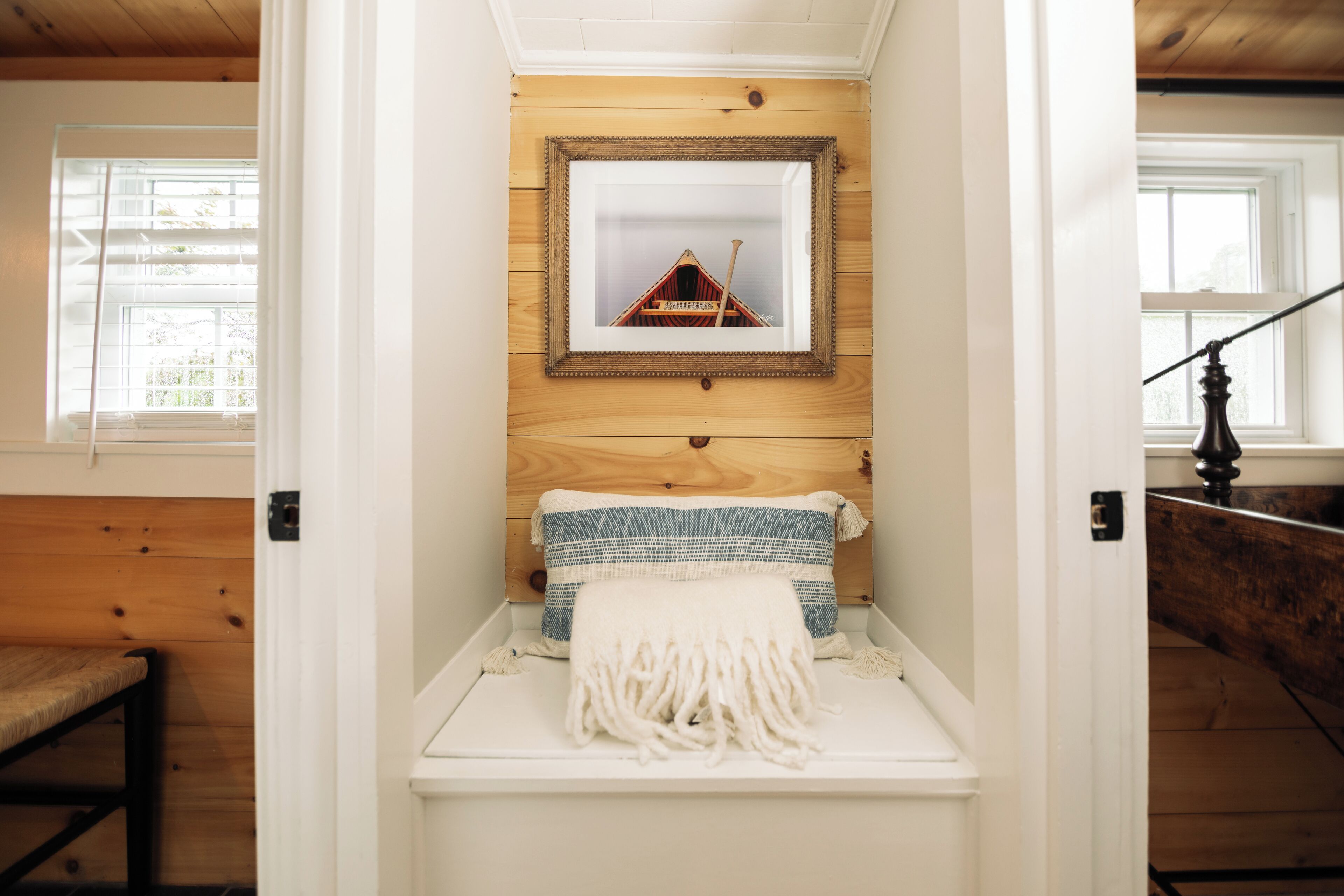 A cozy room with a wooden bench, a framed picture on the wall, and a window with blinds.
