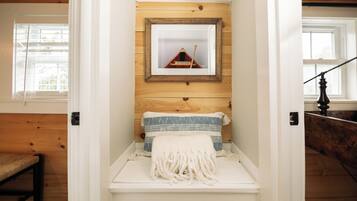 A cozy room with a wooden bench, a framed picture on the wall, and a window with blinds.