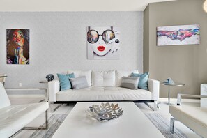 A modern living room with a white sofa, a coffee table with a decorative bowl, and abstract art on the walls.