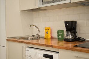 Eine Küche mit einer Edelstahlspüle, einer Kaffeemaschine und einem Geschirrspüler.