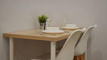 Una mesa de comedor con platos blancos, vasos y una pequeña planta en maceta.