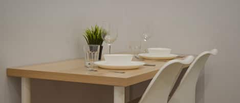 A dining table with white plates, glasses, and a small potted plant.