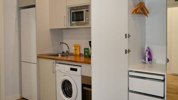 Cocina compacta con lavadora, microondas y lavabo.