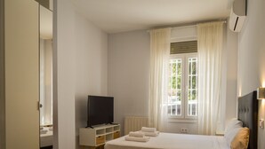 Une chambre d’hôtel avec un lit, une télévision, une fenêtre avec des rideaux et un radiateur.