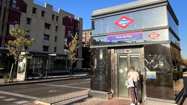 Une station de métro, un ciel d’un bleu éclatant, un abri-bus et un bâtiment orné du logo du métro.
